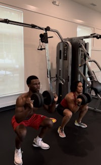 two people doing squats in a gym